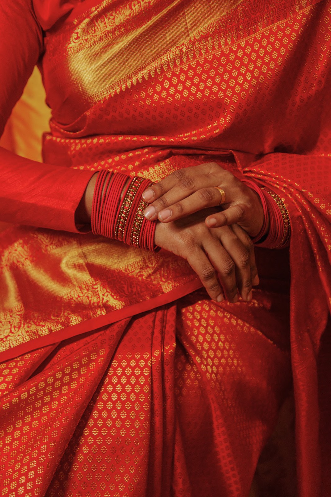 Hands unfolding a silk saree across a shop counter